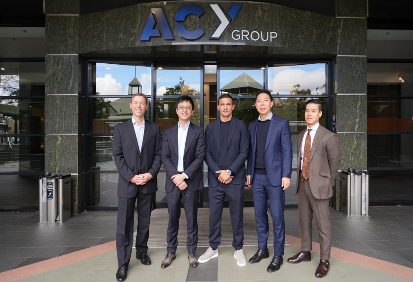 A group of men standing in front of a buildingDescription automatically generated